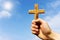 Preacher holding wooden cross against blue sky
