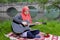 Preaty muslim girl playing acoustic guitar on the river bank