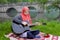 Preaty muslim girl playing acoustic guitar on the river bank