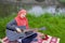 Preaty young muslim girl traying to play acoustic guitar on the river bank