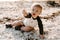 Precious Adorably Cute Happy Baby Boy Toddler Smiling and Playing in the Sand At the Beach Next to the Ocean Water Outside During