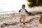 Precious Adorably Cute Happy Baby Boy Toddler Smiling and Playing in the Sand At the Beach Next to the Ocean Water Outside During