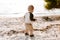 Precious Adorably Cute Happy Baby Boy Toddler Smiling and Playing in the Sand At the Beach Next to the Ocean Water Outside During