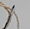 Precision and accuracy. Extreme closeup picture of thread passing through a needle`s eye