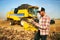 Precision farming. Farmer holding tablet for combine harvester guidance and control with modern automation system