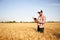 Precision farming. Farmer holding tablet pc, using online data management software at wheat field. Agronomist working