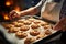 With precision, a seasoned chef carries a tray of oven fresh, steamy cookies