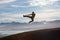 Precision technique on the mountain. A male kickboxer flying through the air as he practises his fly kick technique.