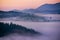 Predawn time in the highlands. A small village among the mountains in the fog, the red sky just before sunset and the silhouettes