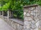 Prefab metal fence on concrete foundation pile of stones loose stone construction of houses and yards construction works