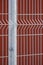 Prefabricated fence post and grating wire panels with blurred red steel wall background