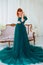 Pregnancy beauty. Beautiful elegant readhead pregnant woman in green dress posing in tender home interior.