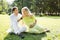 Pregnancy couple laughing and eating chocolate candies in a park on the grass