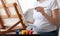 Pregnancy And Leisure. Unrecognizable Pregnant Woman Painting On Easel At Home, Closeup
