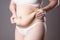 Pregnancy line - linea nigra, tummy tuck, overweight female body and flabby belly on gray background