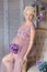 Pregnancy, motherhood and happy future mother concept - pregnant woman in airy violet dress with bouquet flowers against colorful