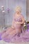 Pregnancy, motherhood and happy future mother concept - pregnant woman in airy violet dress with bouquet flowers against colorful