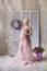 Pregnancy, motherhood and happy future mother concept - pregnant woman in airy violet dress with bouquet flowers against colorful