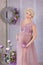 Pregnancy, motherhood and happy future mother concept - pregnant woman in airy violet dress with bouquet flowers against colorful