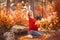 Pregnancy. Motherhood. Pregnant woman hugging her belly enjoying in autumn forest park. Beautiful blond woman in red knit sweater