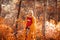 Pregnancy. Motherhood. Pregnant woman hugging her belly enjoying in autumn forest park. Beautiful blond woman in red knit sweater