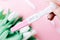 Pregnancy test couple. Positive woman pregnant test in hands with pink silk ribbon on tulips flower pink background. New