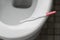 Pregnancy test stick lies on the toilet bowl.
