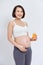 Pregnant asian people standing on white room, she drinking fresh orange juice, she use her hand holding a glas