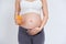 Pregnant asian people standing on white room, she drinking fresh orange juice, she use her hand holding a glas