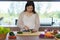 Pregnant Asian woman cutting cucumber for fresh green salad, female prepares tasty organic dinner at home, healthy nutrition for