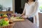 Pregnant Asian woman cutting cucumber for fresh green salad, female prepares tasty organic dinner at home, healthy nutrition for