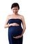 Pregnant asian woman supporting her belly with hands.