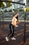 Pregnant, athletic girl on a street sports ground training with a rubber expander