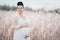 Pregnant beautiful woman in white lace boho dress standing in reeds and holding her belly