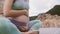 Pregnant belly with hands on it. Woman doing yoga sitting in lotus outdoors