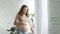 Pregnant belly woman standing in room. Expecting mother looking window at home