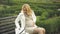 Pregnant blond woman taking pill, sitting on park bench, feeling abdominal pain