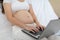 Pregnant business woman sitting and working on the laptop with sale report,tablet,books and sticky note at home,Pregnant of