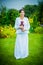 Pregnant country women in a white dress stands with a toy in the garden