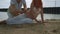 Pregnant couple drawing on beach sand. Love couple relaxing on beach