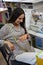 Pregnant dressmaker sits at a sewing machine