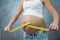 Pregnant female measuring tummy by yellow centimeter