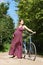 Pregnant girl with bicycle on a forest road, front view