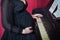 Pregnant girl in a black dress plays piano