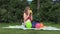 Pregnant girl blow yellow balloon sit on plaid in park