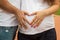 Pregnant girl and future father make heart with hands on tummy background.