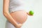 Pregnant girl holding a green apple. nutrition during pregnancy. Vitamins and pregnancy. Source of iron, pregnant anemia.