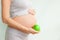 Pregnant girl holding a green apple. nutrition during pregnancy. Vitamins and pregnancy. Source of iron, pregnant anemia.