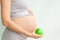 Pregnant girl holding a green apple. nutrition during pregnancy. Vitamins and pregnancy. Source of iron, pregnant anemia.