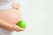 Pregnant girl holding a green apple. nutrition during pregnancy. Vitamins and pregnancy. Source of iron, pregnant anemia.